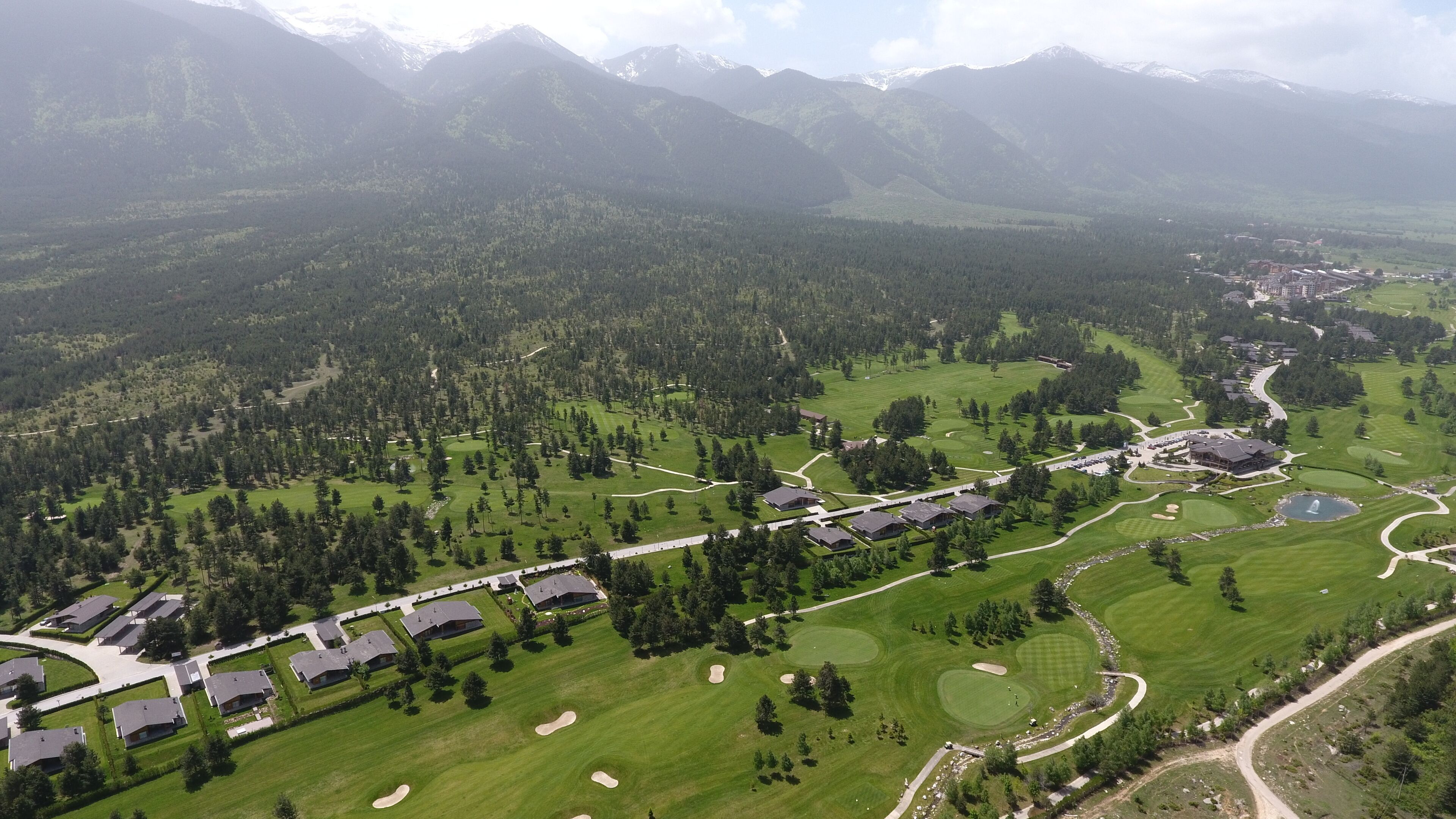 An aerial view of a golf course with a residential area, including houses and a clubhouse.
