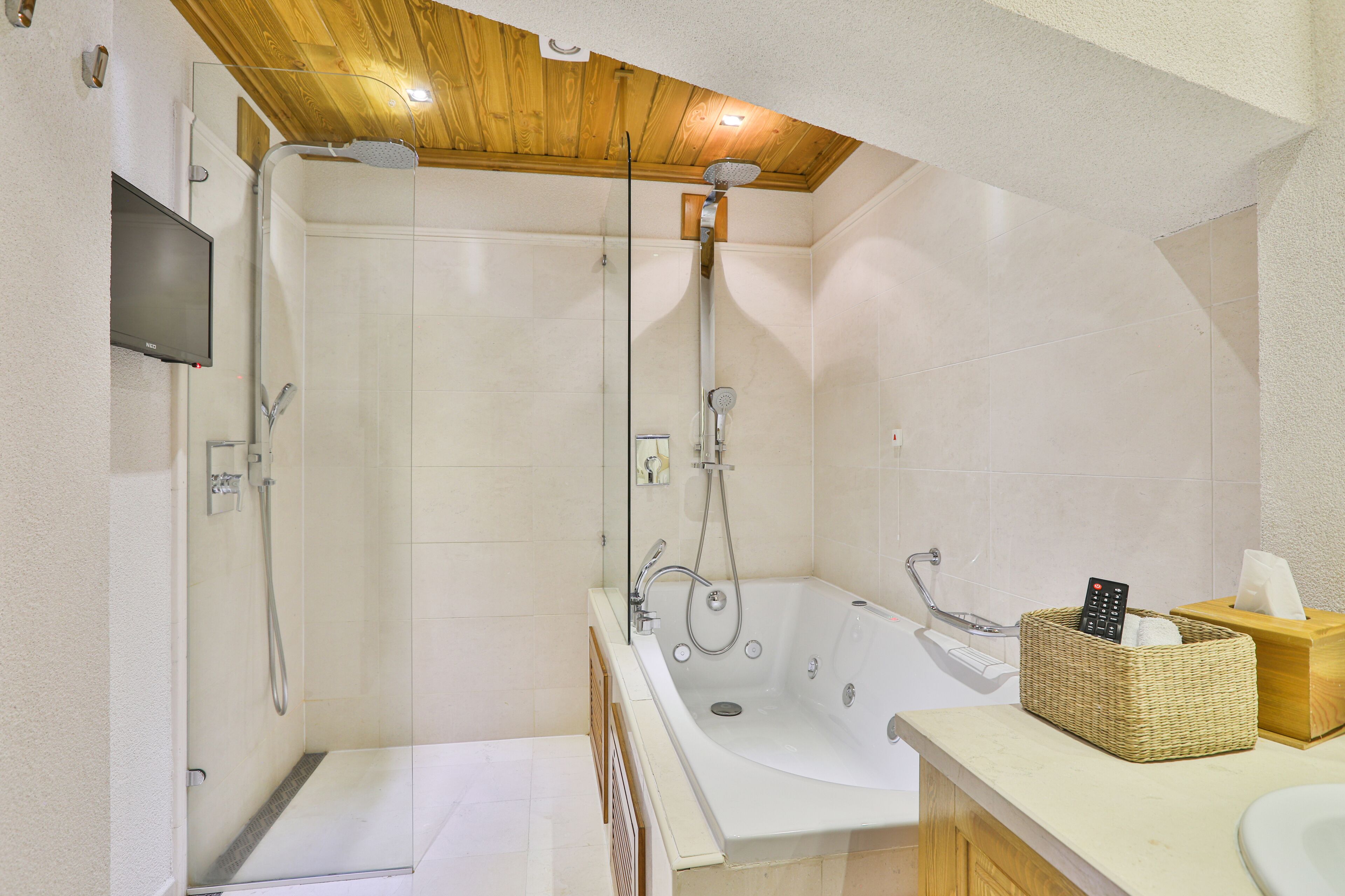 Une salle de bain moderne équipée d’une douche, d’une baignoire et d’un meuble-lavabo avec un évier et un téléviseur.