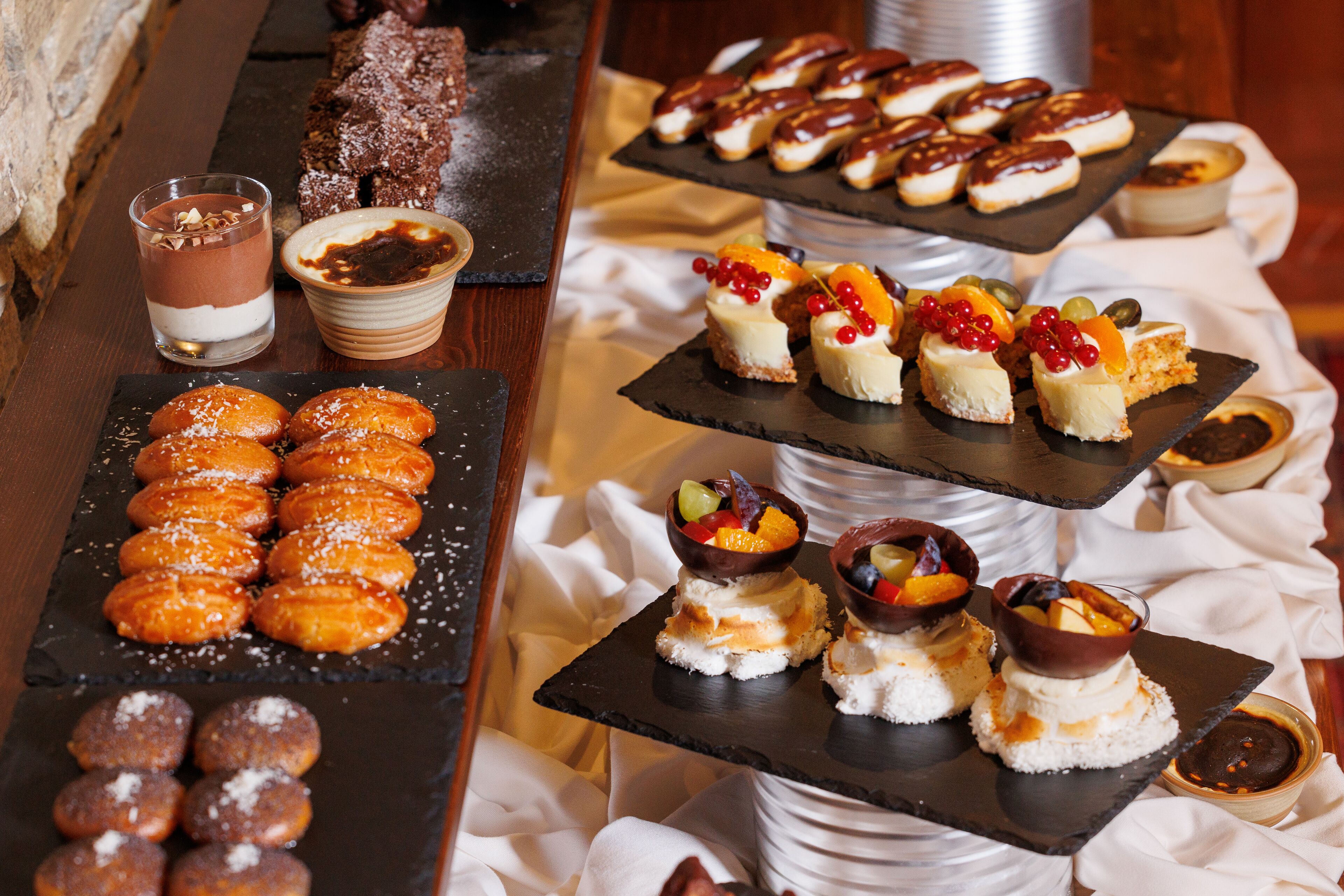 Une variété de desserts et de pâtisseries sont présentés sur une table de buffet, notamment de la mousse au chocolat, des gâteaux décorés de fruits et un assortiment de viennoiseries.