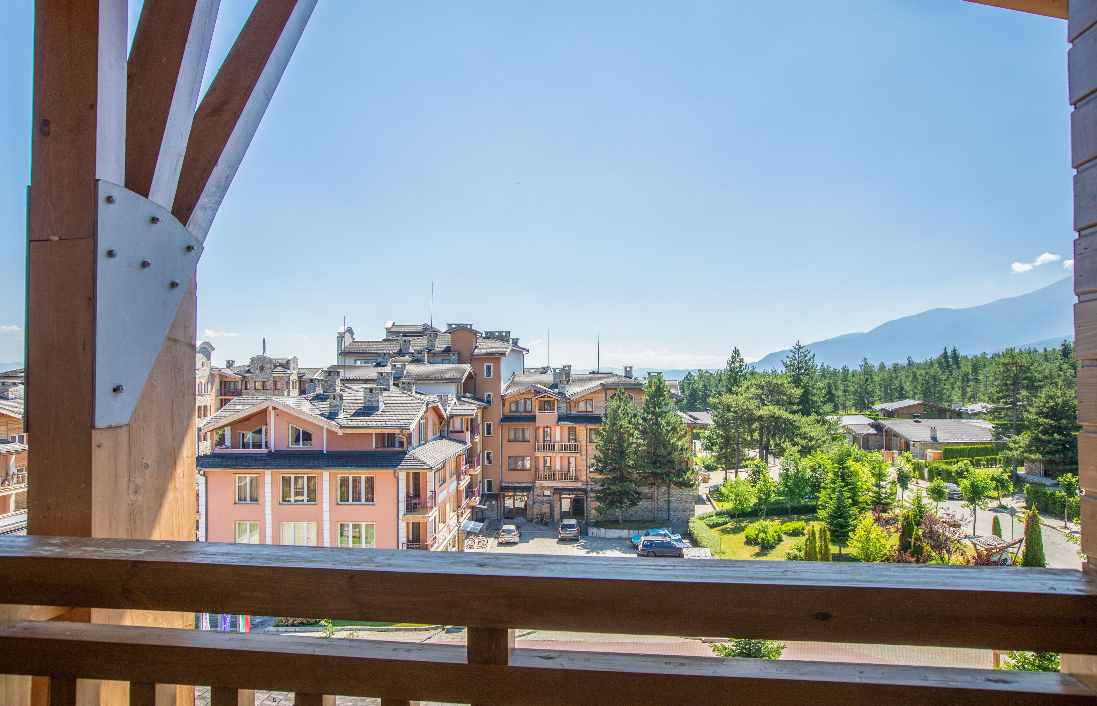 A view of a town with traditional architecture, including multi-story buildings with balconies and a mountain in the background.