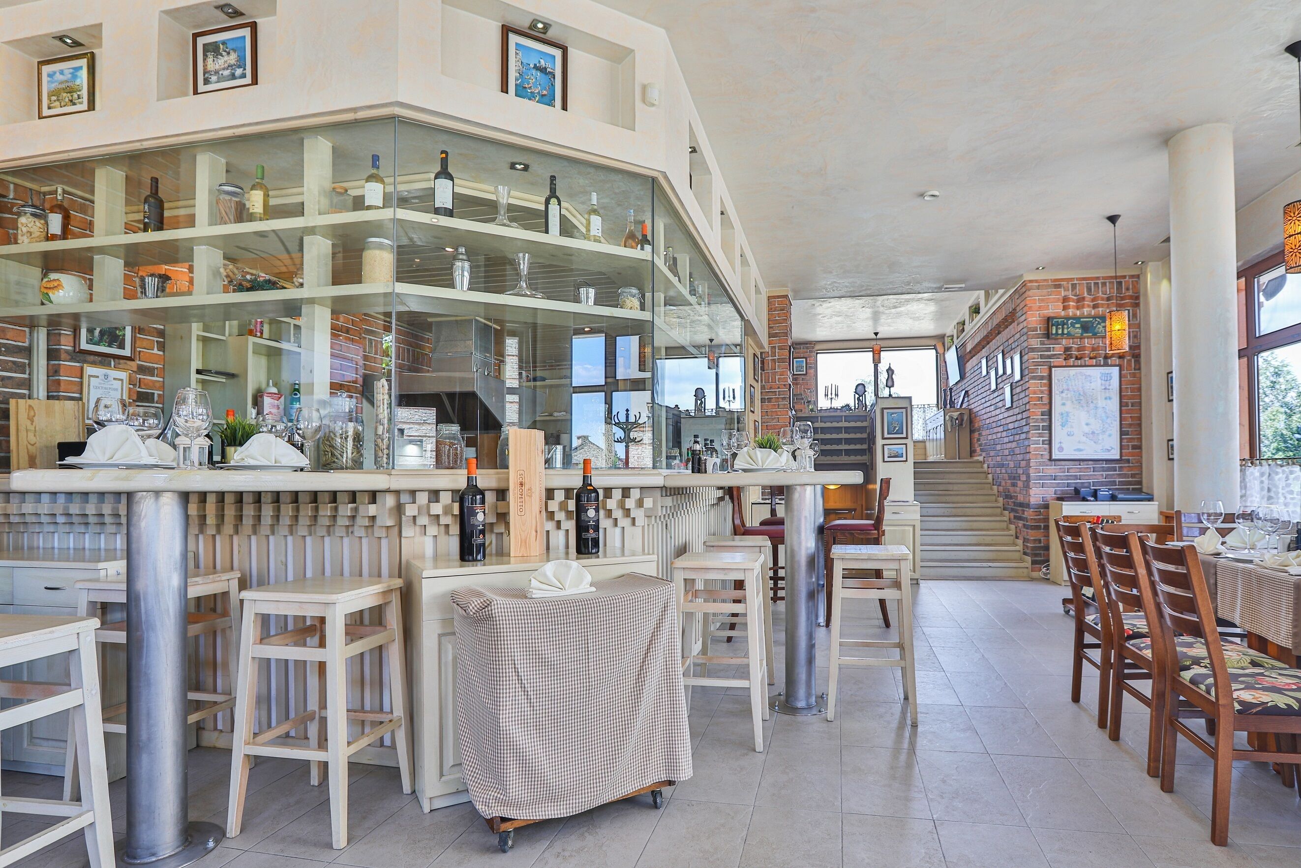 Ein Restaurant mit Barbereich, Holzsesseln und einer Treppe, die in einen oberen Bereich führt.
