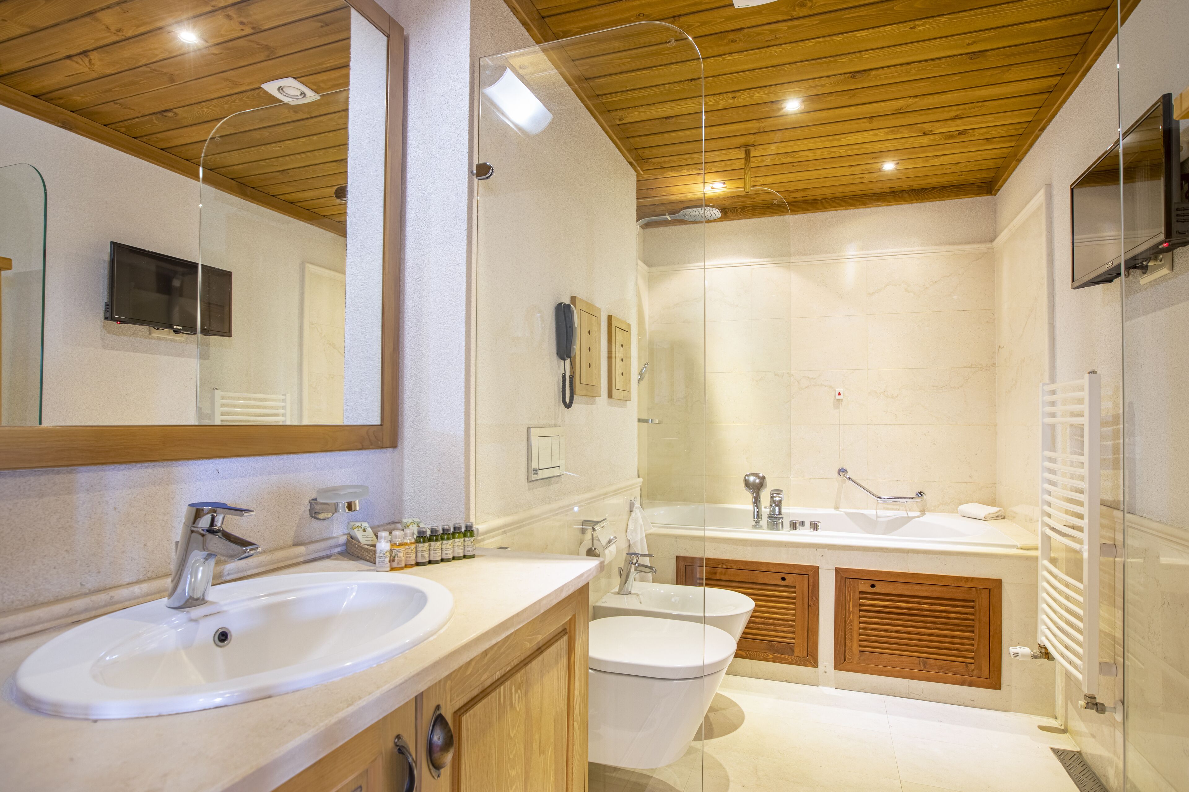 A modern bathroom with a large mirror, two sinks, a shower, and wooden cabinets.