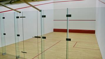Una cancha de squash con paredes de vidrio y piso de madera.