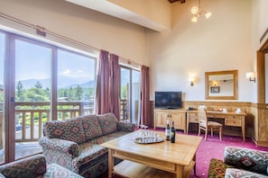 A spacious living room with a large sofa, a wooden coffee table, and a television. There is a desk with a chair and a window with curtains. - Pirin Golf Hotel & SPA (Razlog)