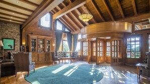 A spacious room with wooden beams, a large curved wooden door, and a green carpet. - Pirin Golf Hotel & SPA (Razlog)