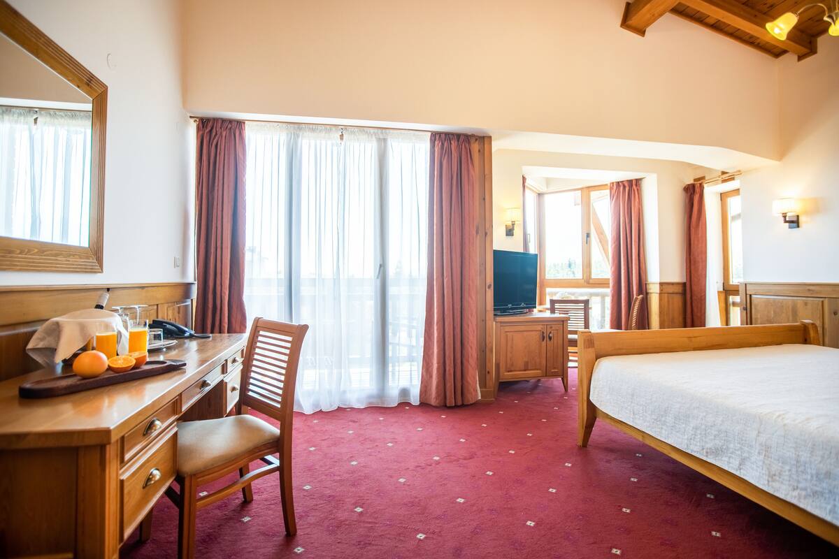 A hotel room with a bed, desk, chair, and a television.