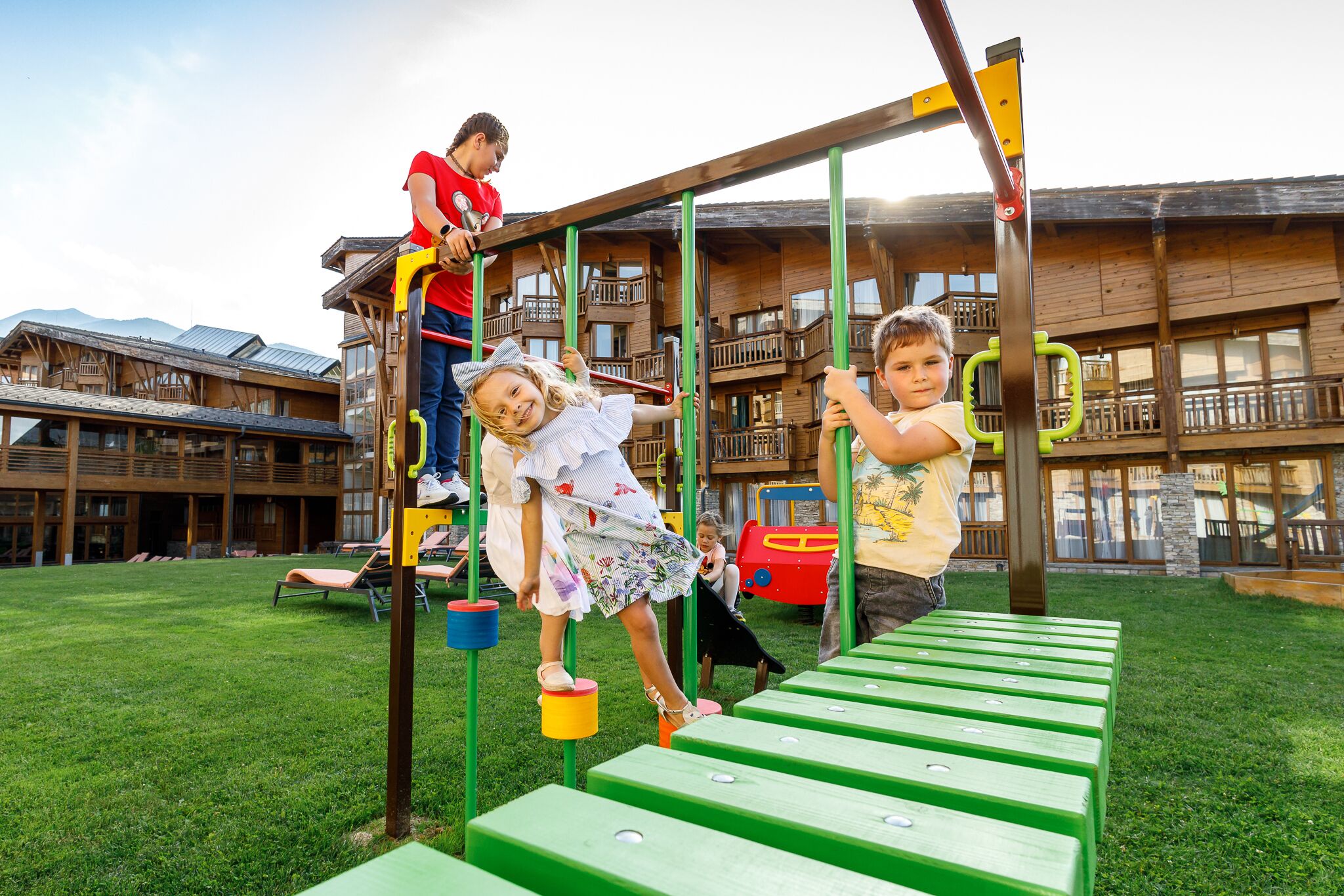 Un parque infantil con una estructura de madera para escalar y un tobogán verde.