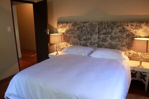 A bedroom with a large bed, two bedside tables with lamps, and a patterned headboard.
