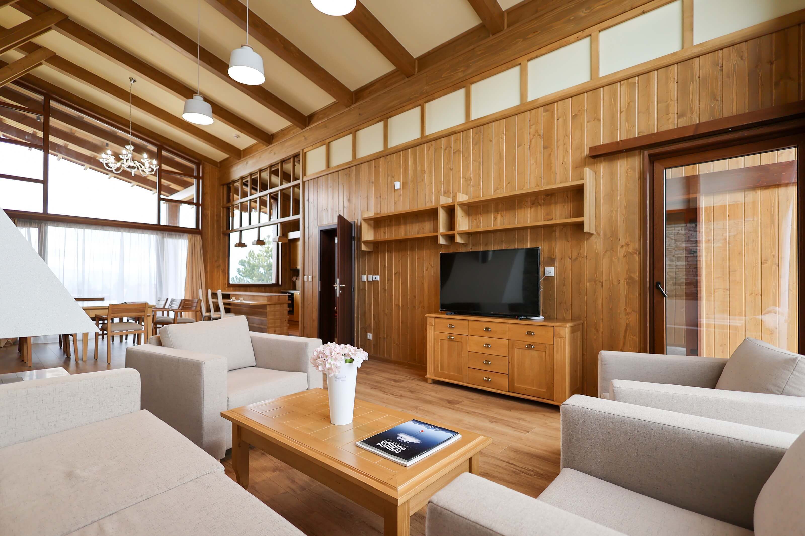 A spacious living room with wooden paneling, a large flat-screen TV, and comfortable seating.