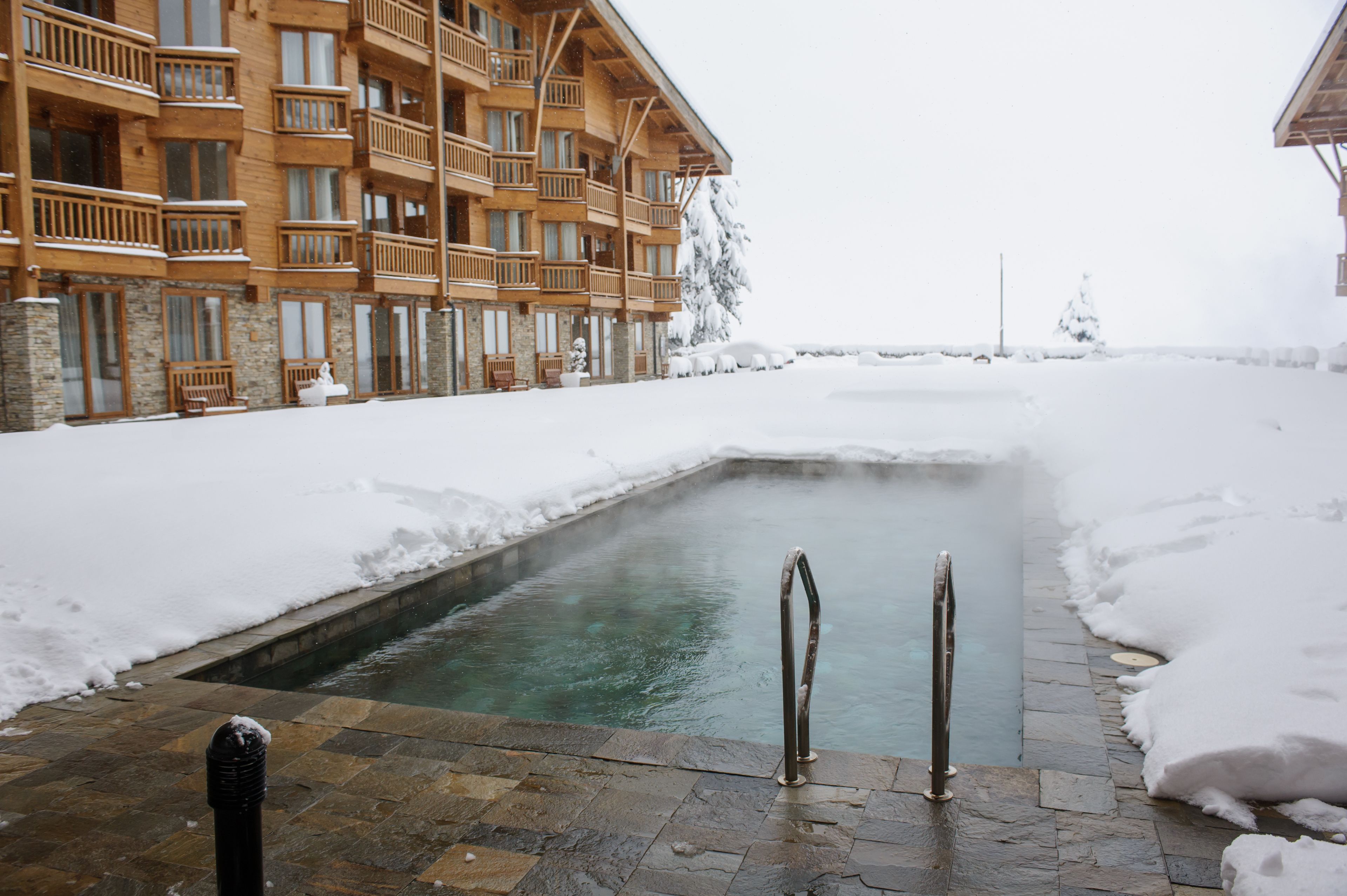 A snow-covered outdoor pool area with a wooden building in the background.