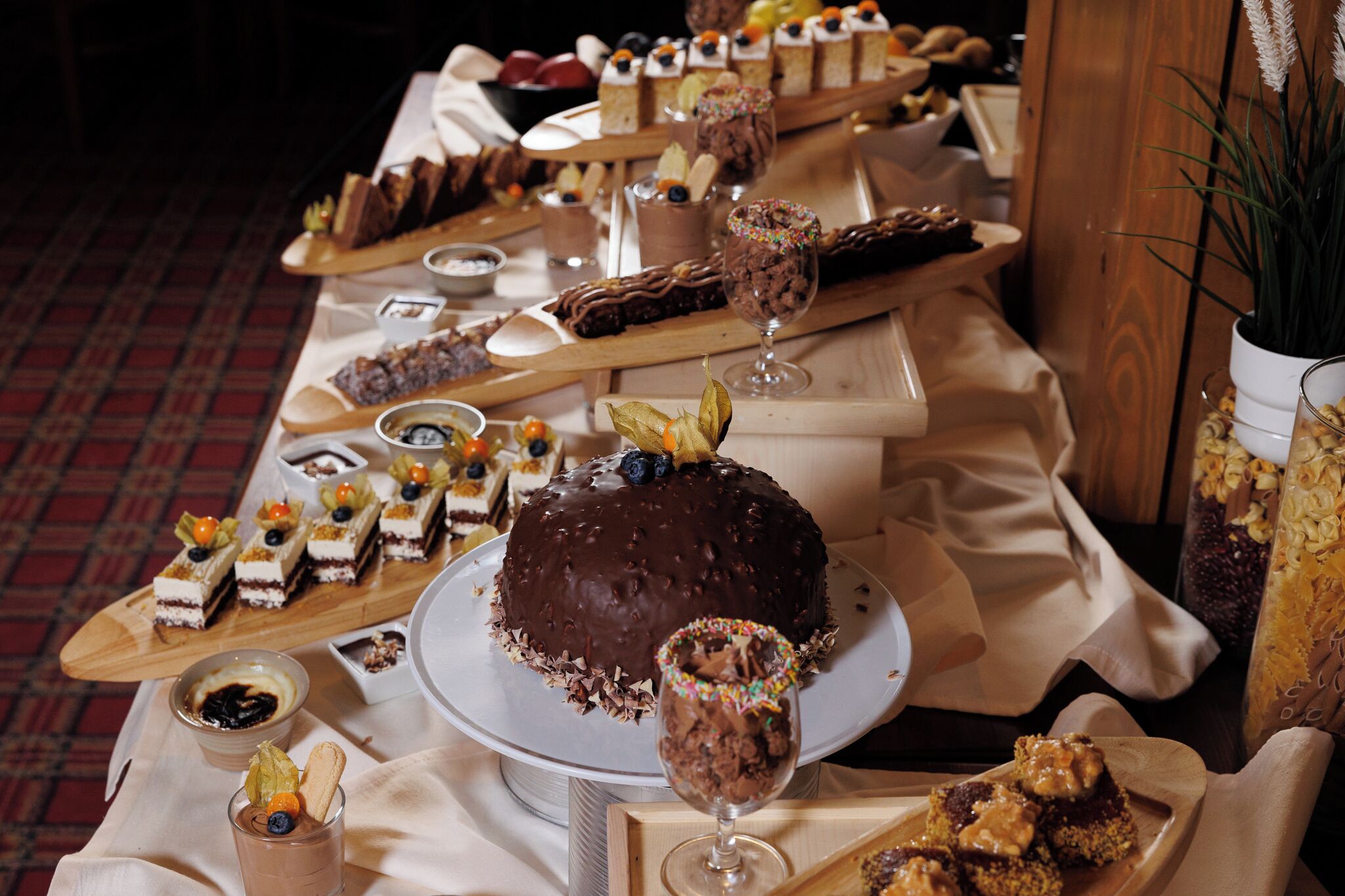 A dessert table with various cakes and pastries, including a chocolate cake with a decorative leaf on top.
