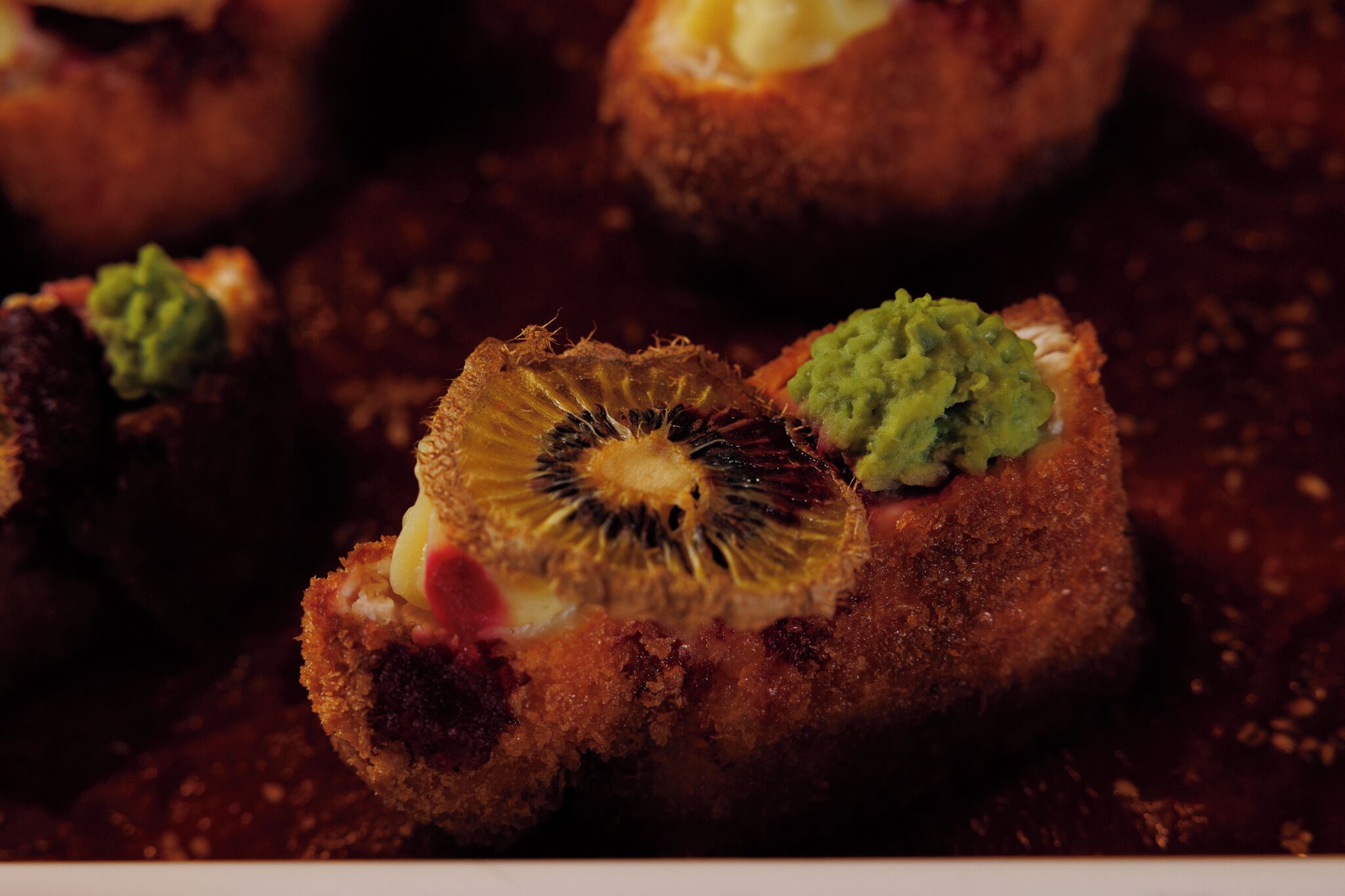 A close-up of a food item with a crispy exterior and a slice of kiwi in the center.