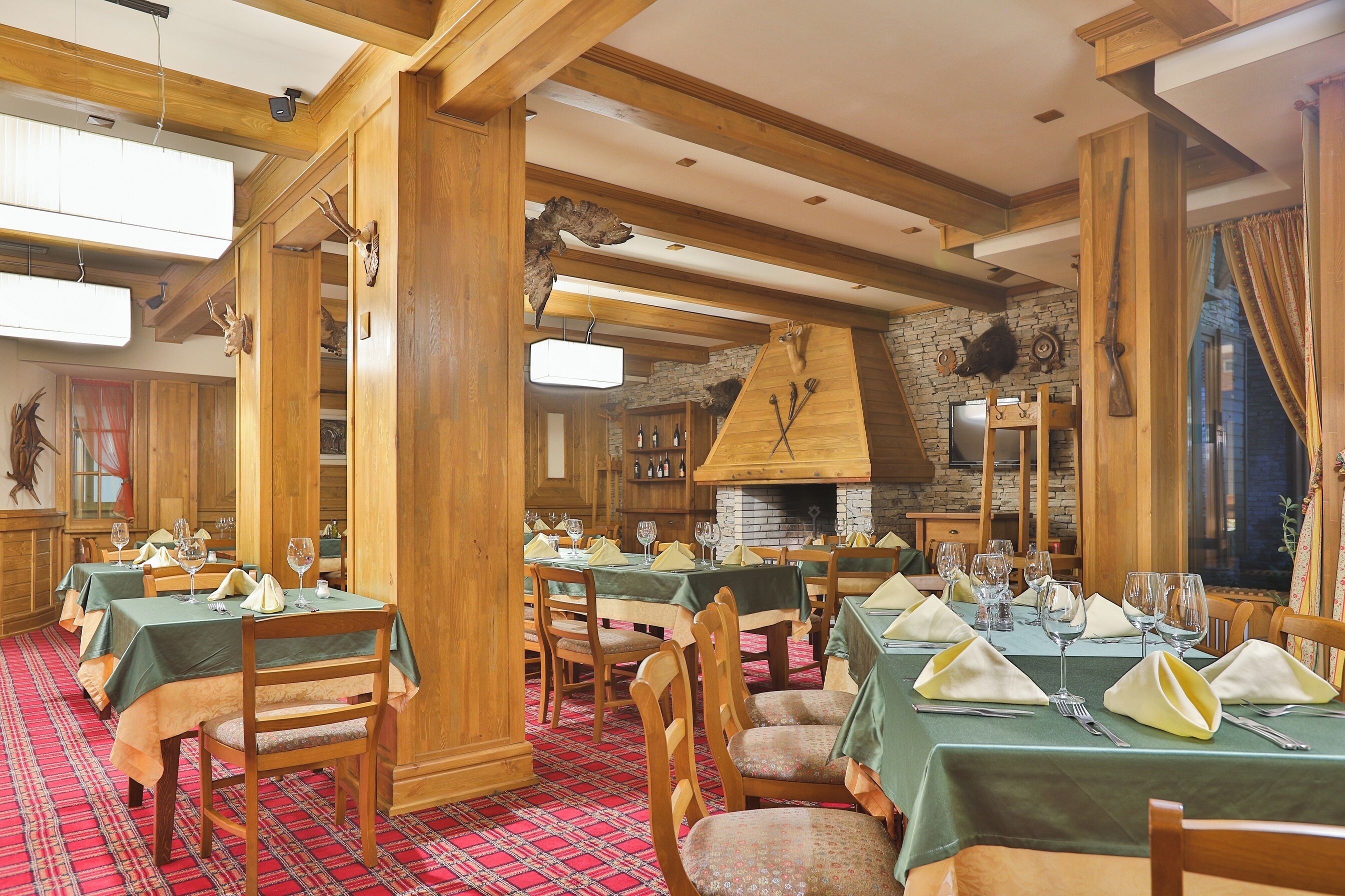 Un restaurante con interiores de madera, varias mesas preparadas para comer y una chimenea de piedra.
