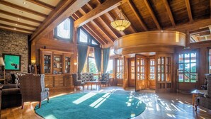 A spacious room with wooden beams, a large curved wooden door, and a green carpet. - Pirin Golf & Country Club Apartment Complex (Razlog)