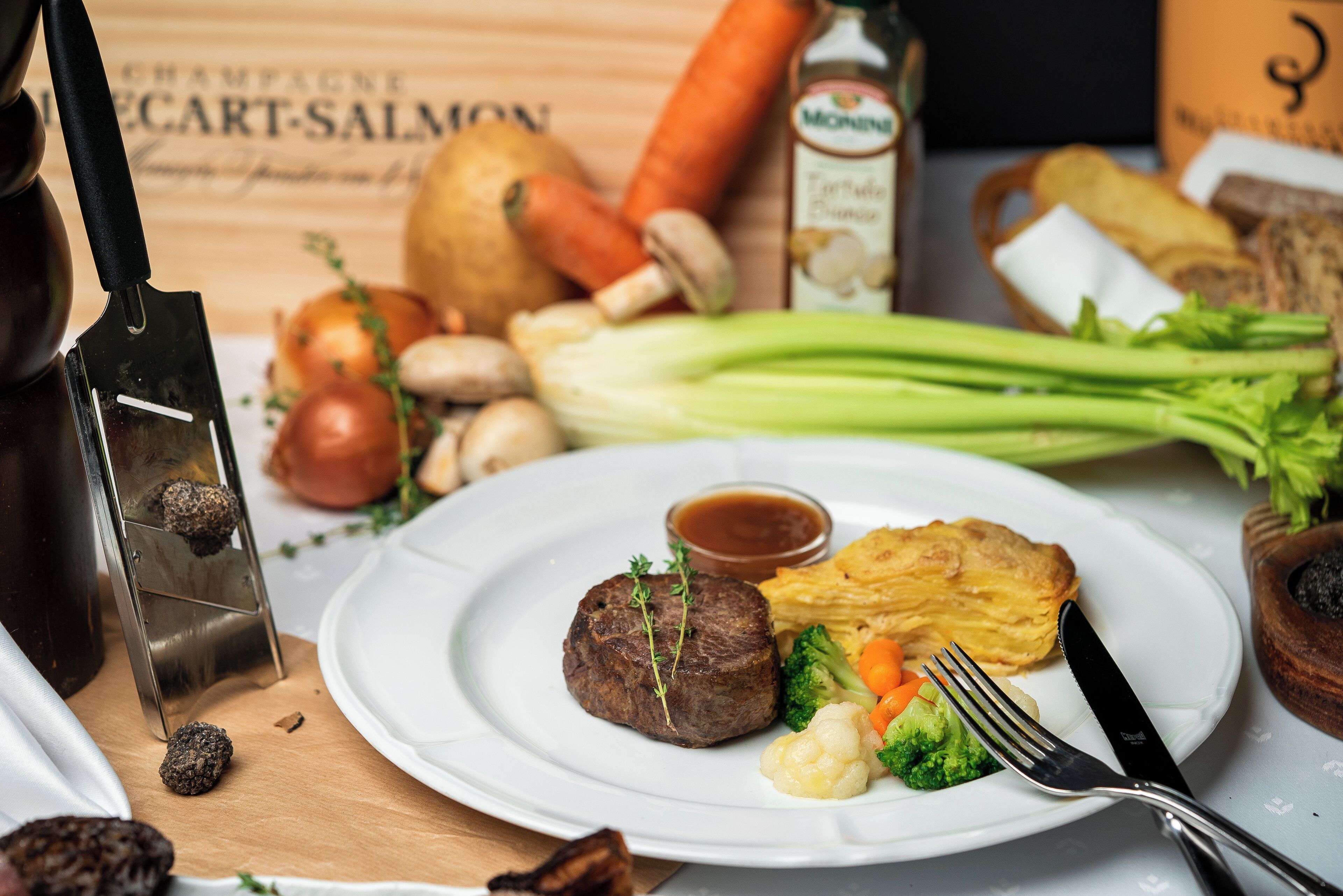 A plate with steak, vegetables, and a small bowl of sauce.