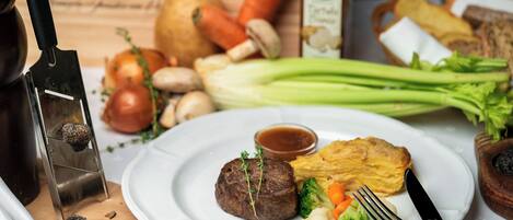 A plate with steak, vegetables, and a small bowl of sauce.