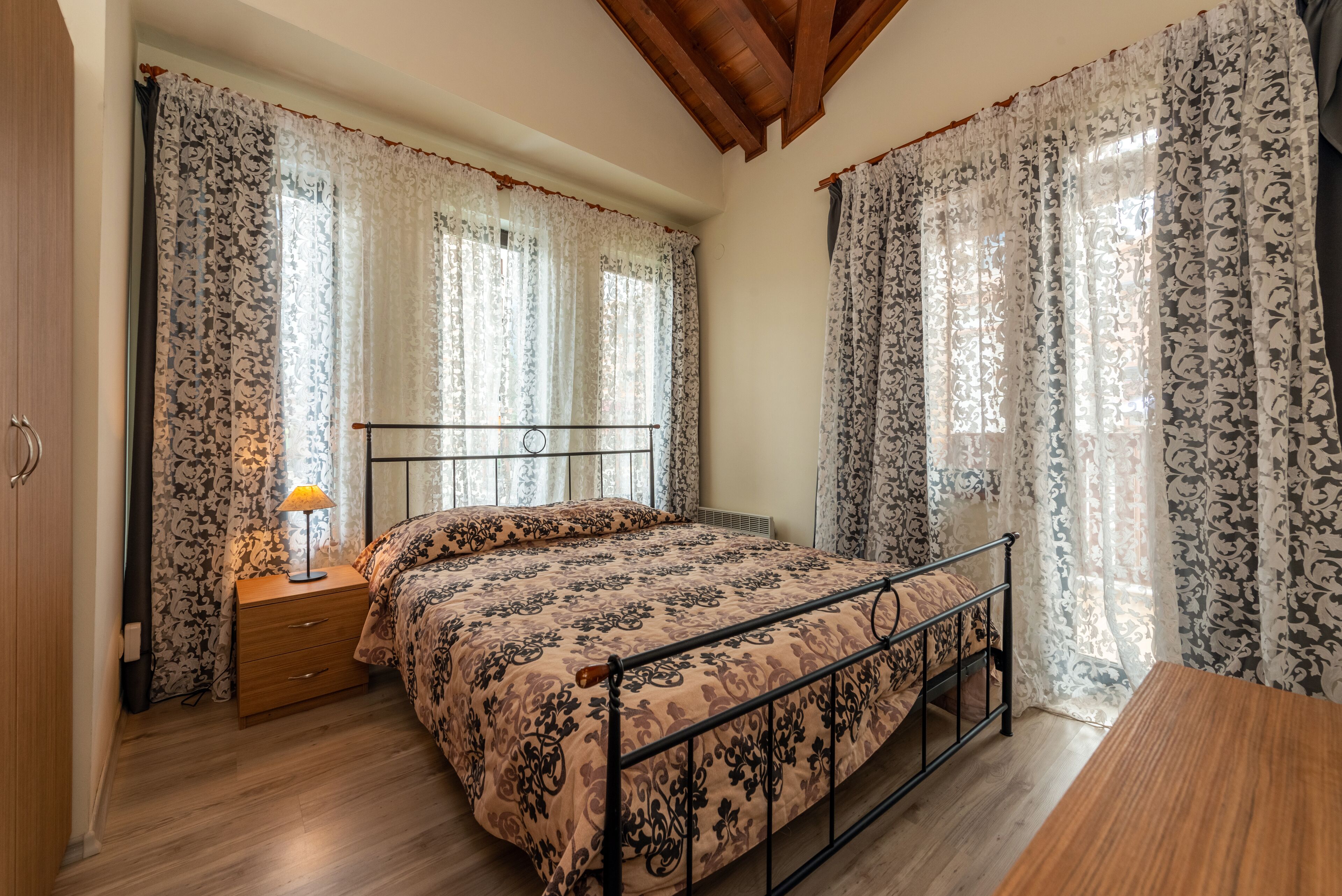 A bedroom with a bed, wooden nightstand, and a table.