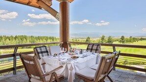A dining table set for four with a scenic view of a golf course and mountains. - Pirin Golf & Country Club Apartment Complex (Razlog)