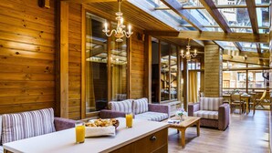 A cozy wooden cabin interior with a dining area, sofas, and a breakfast bar. - Pirin Golf & Country Club Apartment Complex (Razlog)