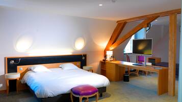 A hotel room with a bed, bedside tables, a desk with a computer, and a TV.