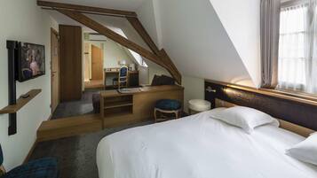 A modern hotel room with a lofted sleeping area, a desk, and a television.