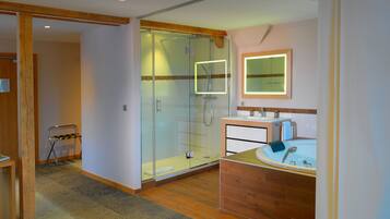 A modern bathroom with a glass-enclosed shower, a wooden vanity with a sink, and a mirror with a lighted frame.