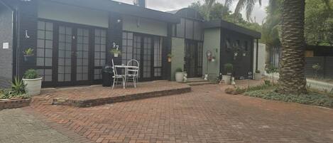 Un edificio moderno con un patio de ladrillo, mobiliario exterior y plantas en macetas.