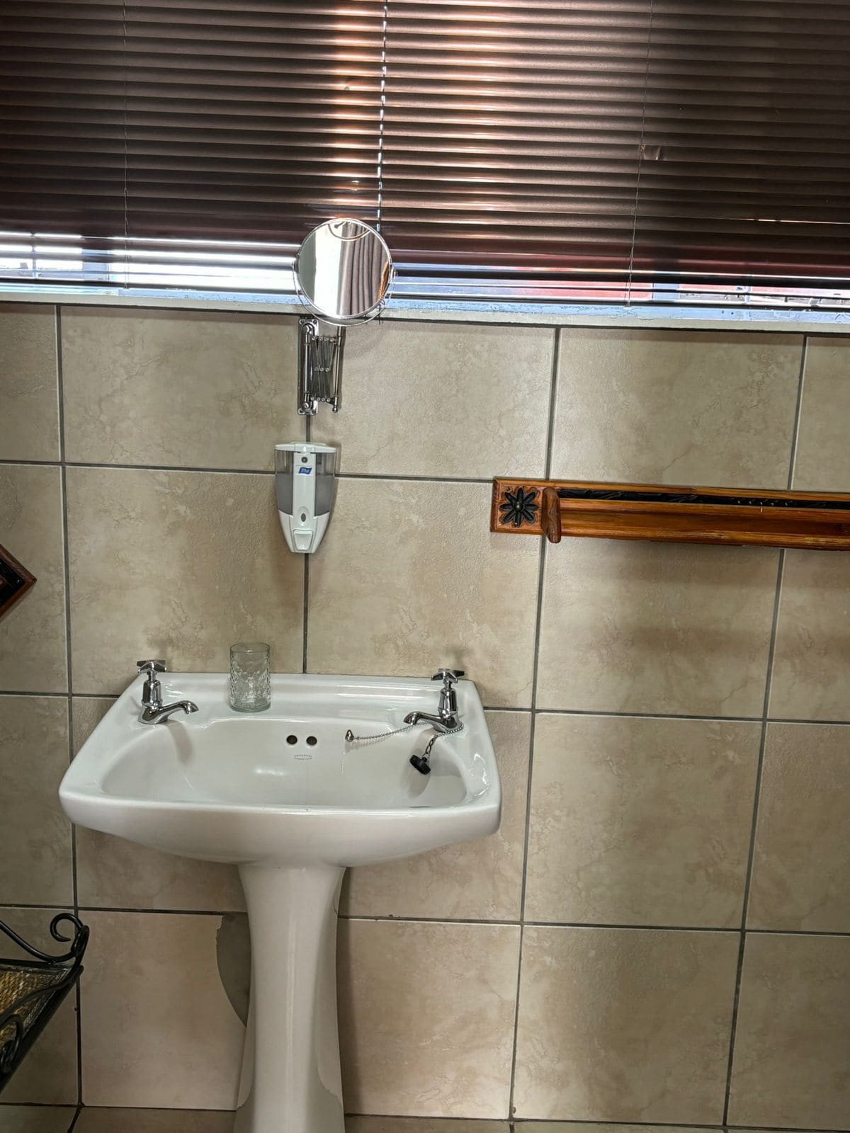 A bathroom with a white sink, a mirror, and a towel rack.