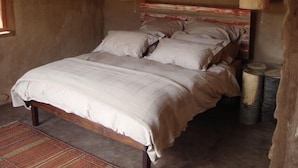 A bed with a wooden frame and a headboard with a striped pattern. There is a rug on the floor and a trash can to the right. - Cedar Falls (Willowmore)