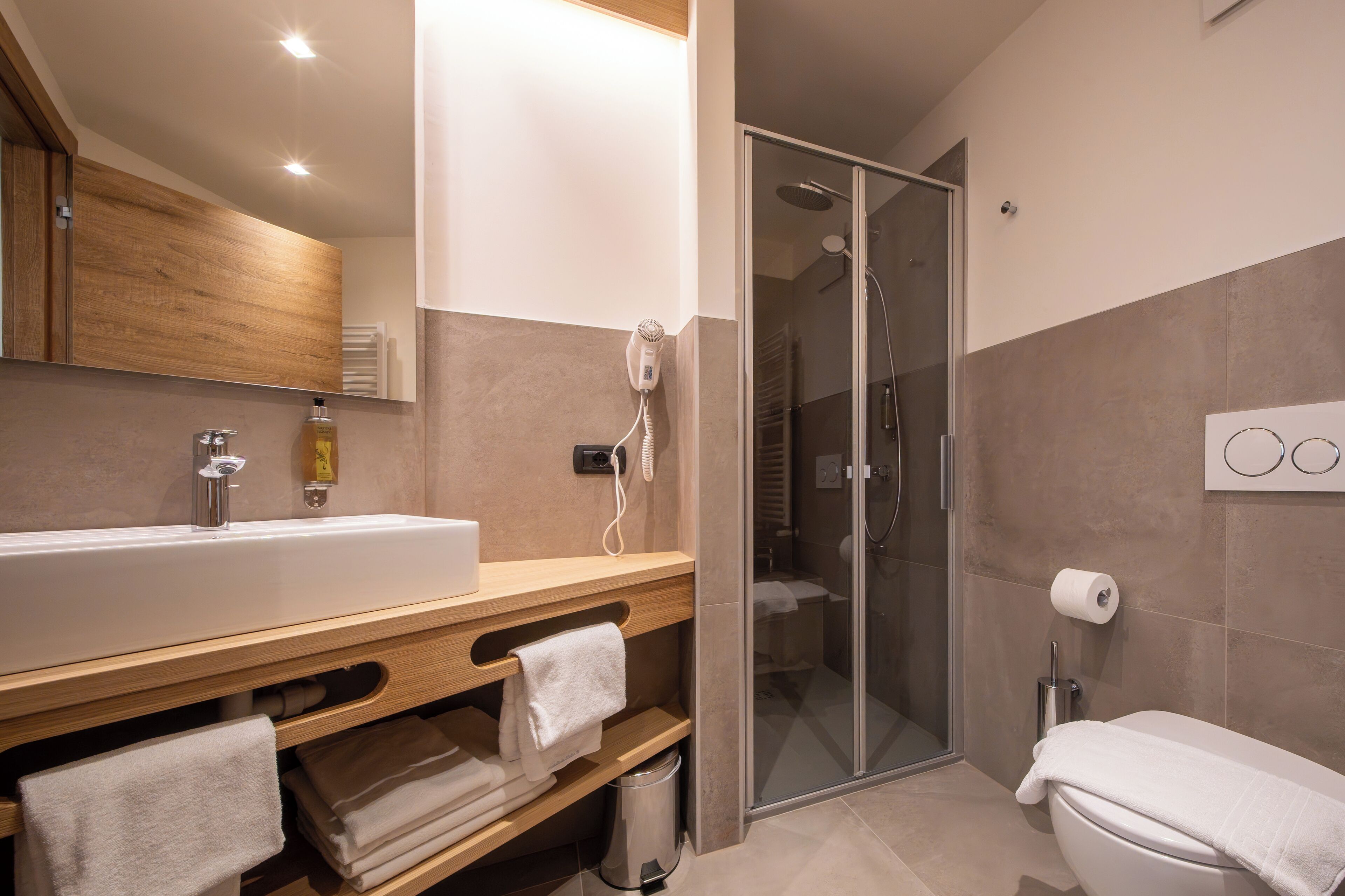 Un bagno moderno con un lavandino capiente, un box doccia in vetro e un water.
