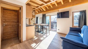 Un interior moderno con techo de madera, zona de comedor, sofá y balcón con vistas.