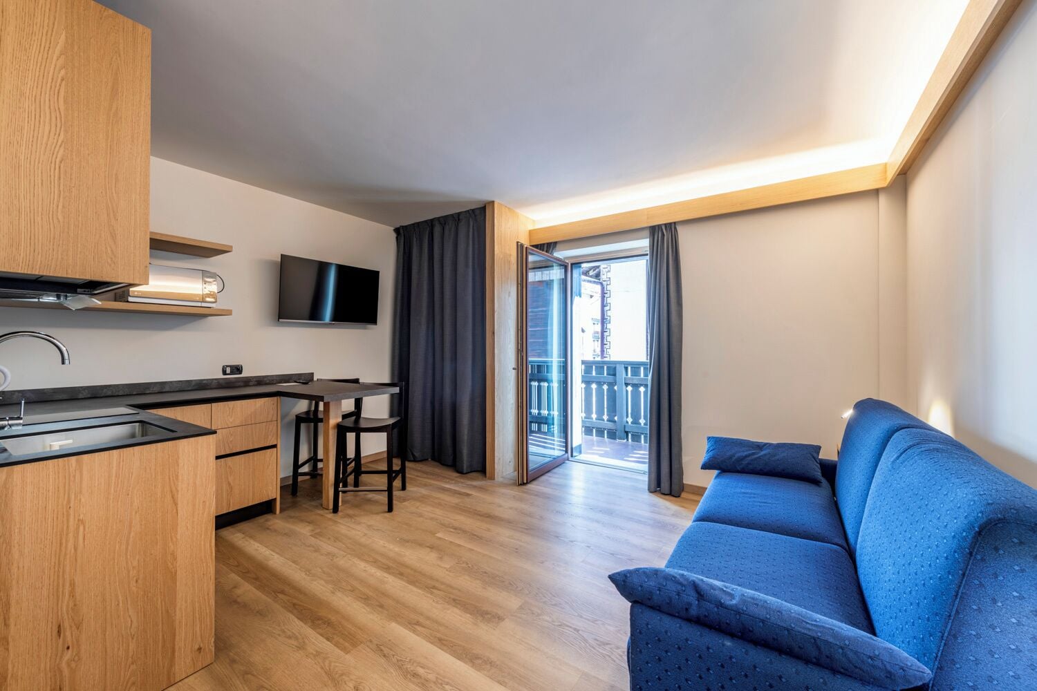 Un appartement moderne doté d’une kitchenette, d’un coin repas, d’un canapé et d’un balcon.
