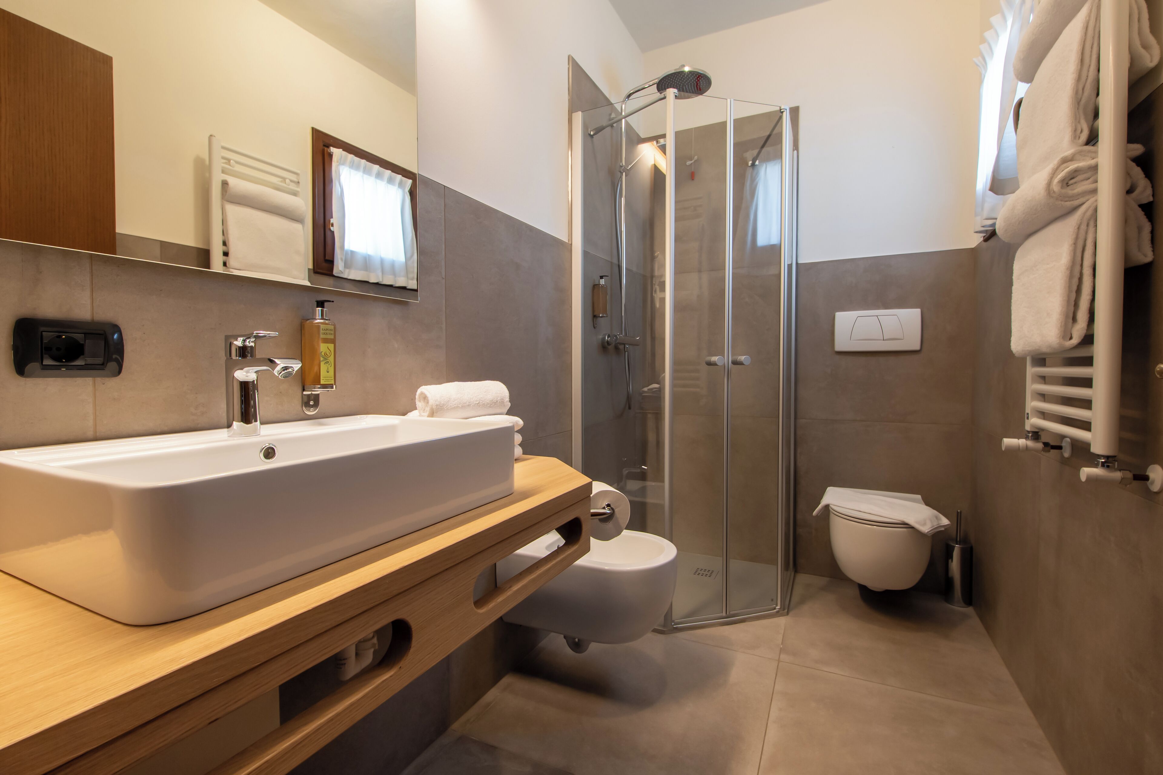 Ein modernes Badezimmer mit einem großen Waschbecken, Toilette und einer Duschkabine aus Glas.