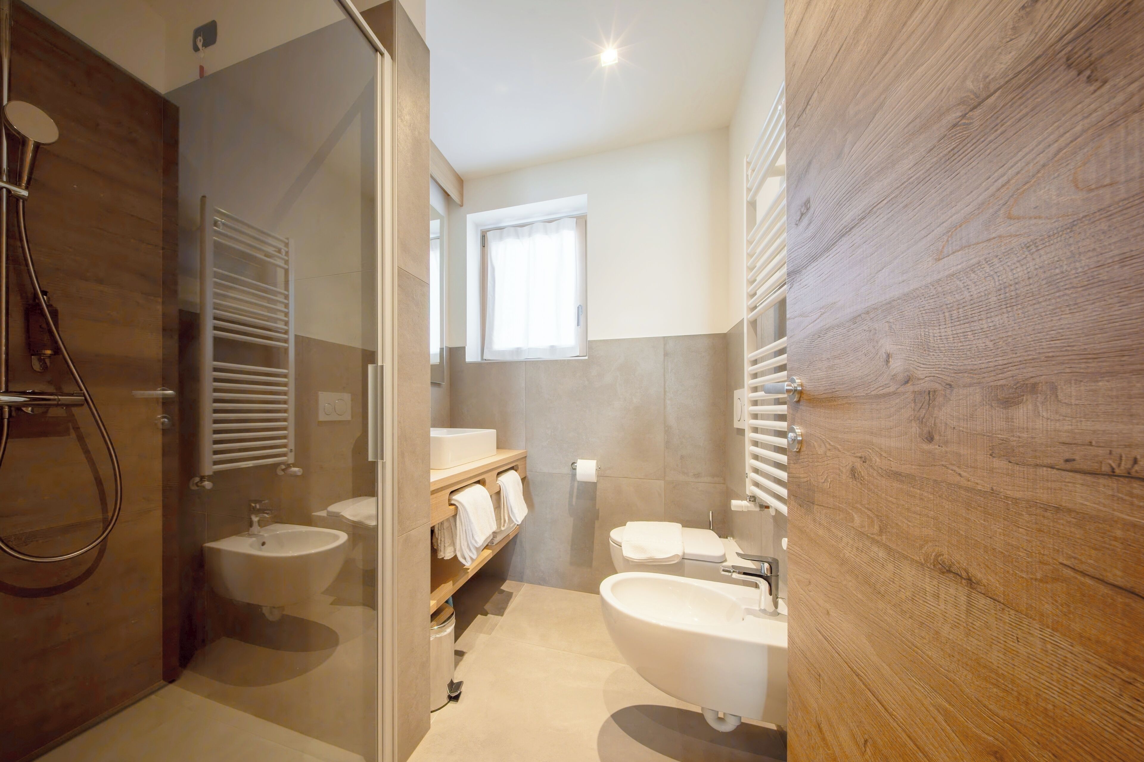 A modern bathroom with a glass-enclosed shower, a vanity with a sink and mirror, and a wooden accent wall.