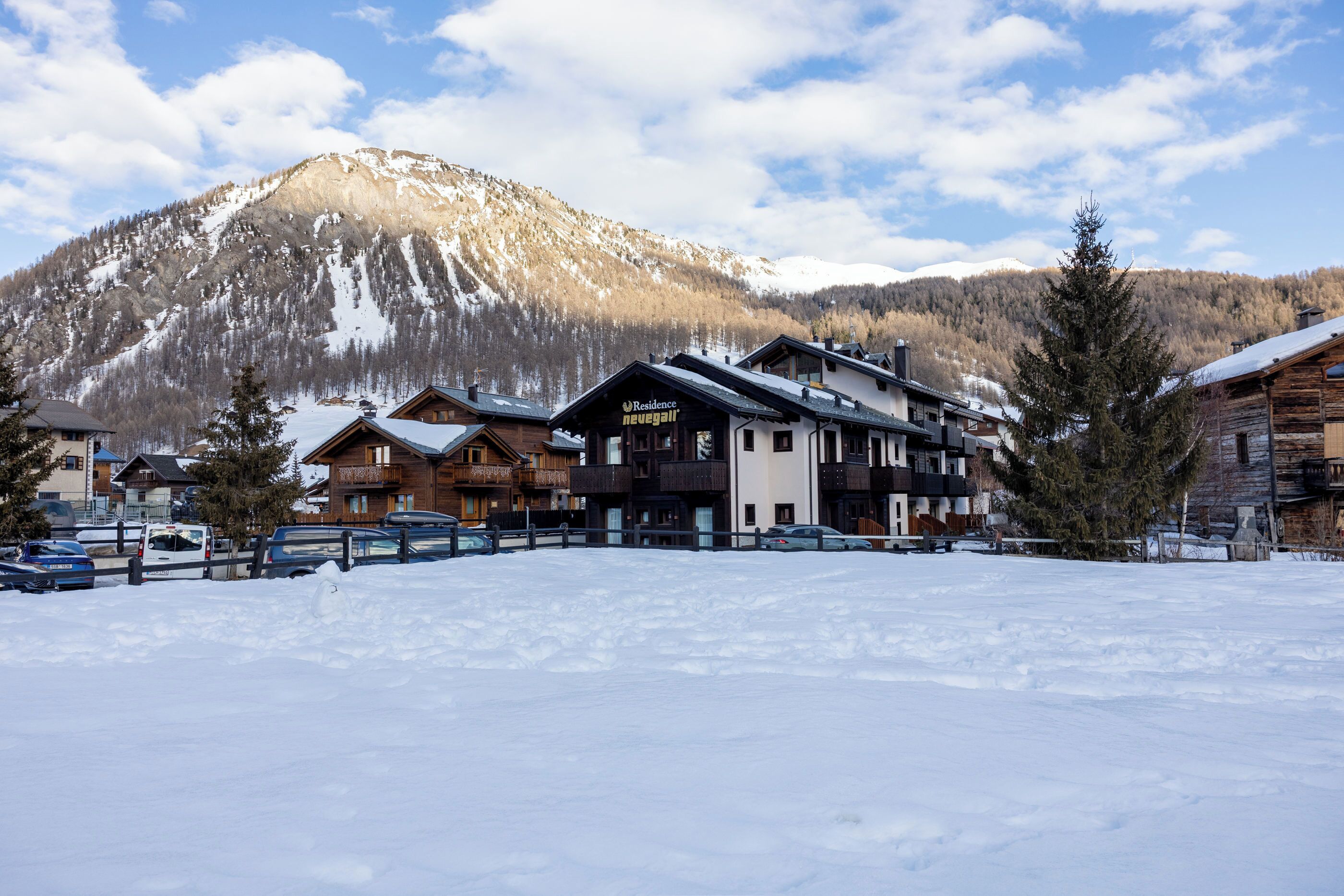 A hotel with multiple floors, a covered outdoor area, and a view of snow-covered mountains.