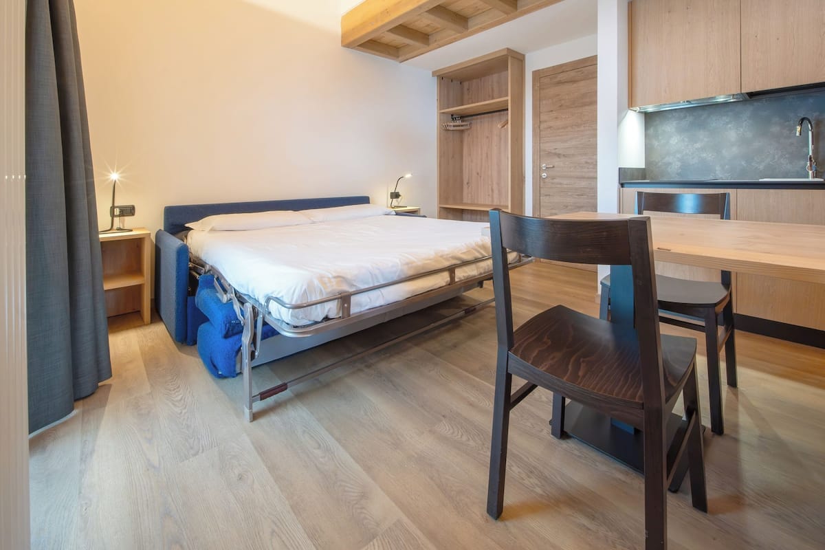 Una camera compatta con un letto, una scrivania e angolo cottura.