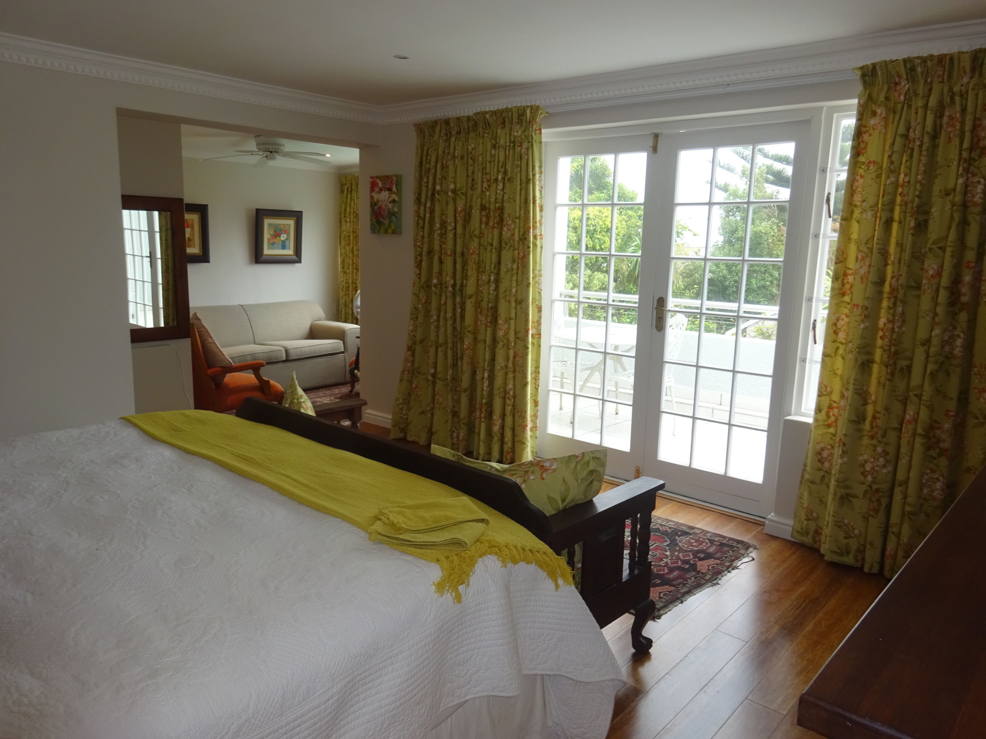 A bedroom with a large bed, a sofa, and a window with curtains.