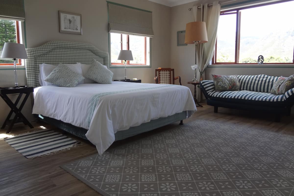 Um quarto com cama, sofá, luminária e janela.