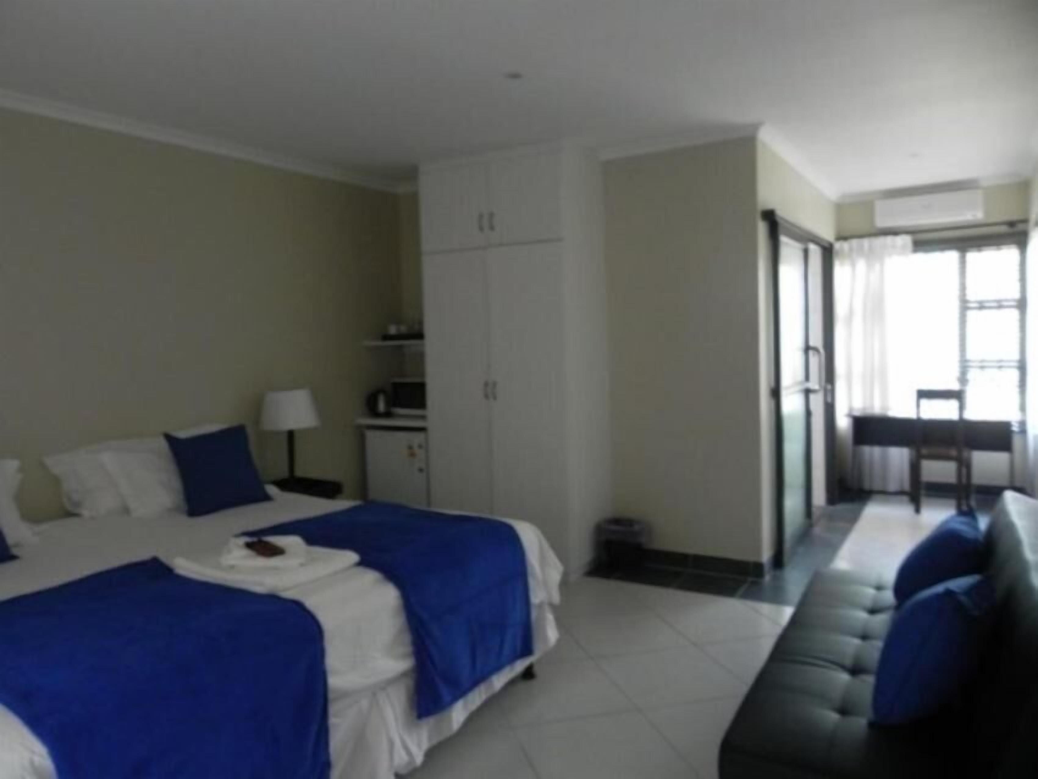 Habitación de hotel con dos camas, un escritorio, una silla y un sofá.