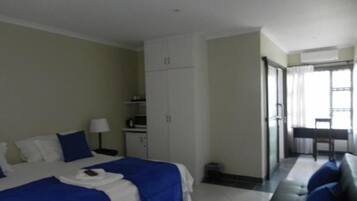 Habitación de hotel con dos camas, un escritorio, una silla y un sofá.