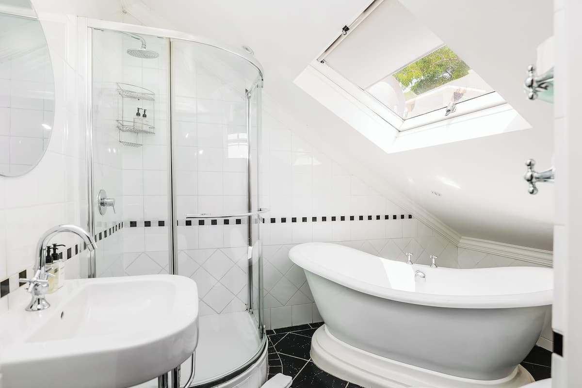 Ein modernes Badezimmer mit einer gläsernen Duschkabine, einer freistehenden Badewanne und einem Oberlicht.