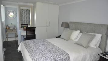 A bedroom with a bed, bedside table, lamp, and wardrobe.