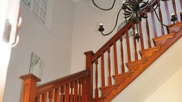 Un escalier en bois, un lustre, une chaise et une petite table avec une plante.