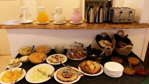 A breakfast buffet with various dishes, beverages, and utensils. - Kelta Hotel Puerto Iguazú Centro (Puerto Iguazú)
