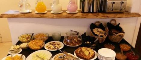 Un bufé de desayuno con diversos platos, bebidas y utensilios.