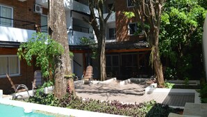 A courtyard with a pool, lounge chairs, and a covered seating area surrounded by trees and plants. - Kelta Hotel Puerto Iguazú Centro (Puerto Iguazú)
