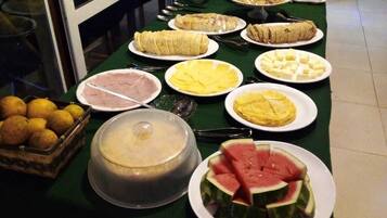 A buffet table with various food items including sliced watermelon, cheese, and other dishes.