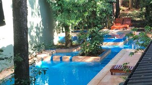 A swimming pool with steps leading into it, surrounded by trees and a wooden deck. - Kelta Hotel Puerto Iguazú Centro (Puerto Iguazú)