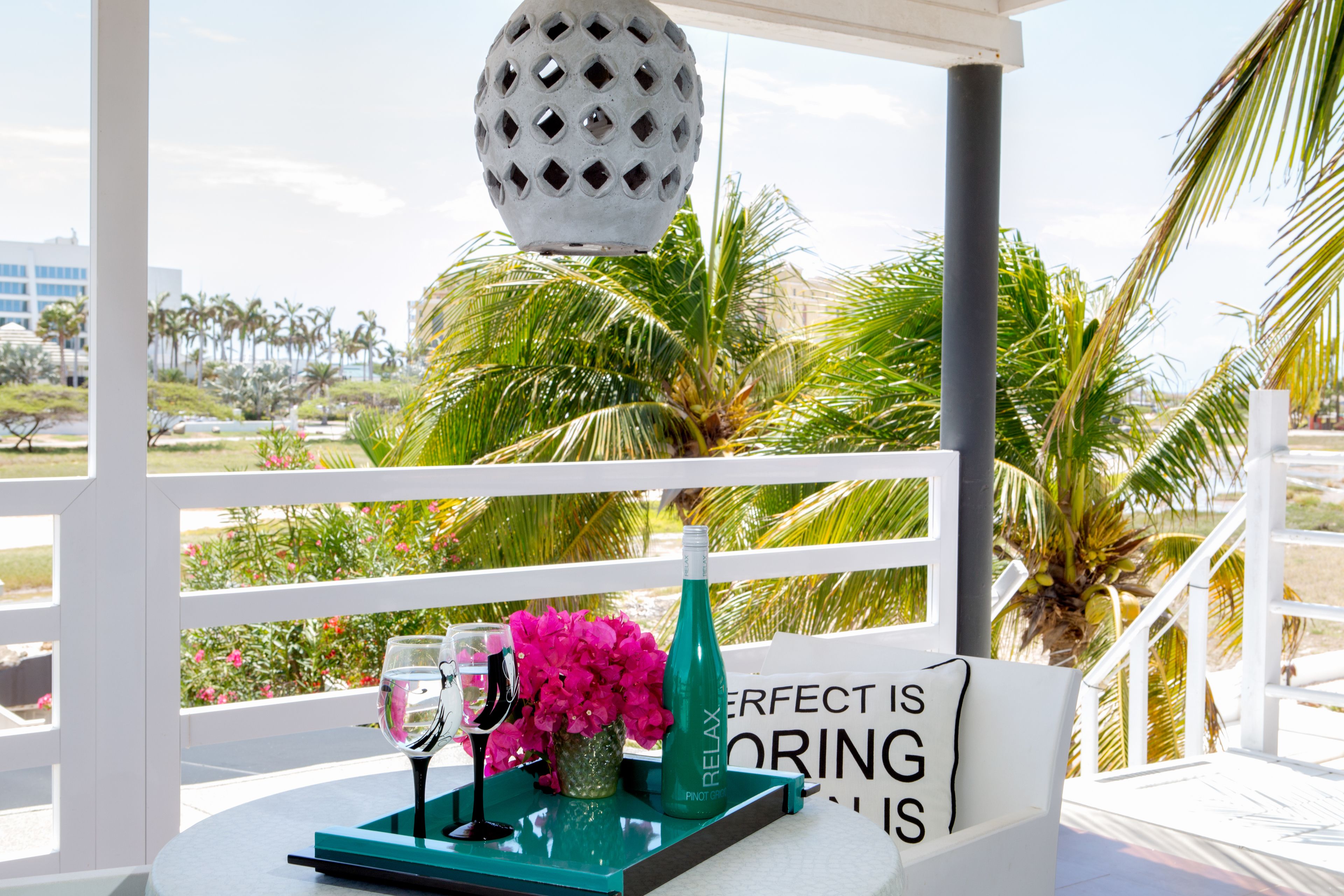 A table with a bottle, glasses, and flowers, with a sign saying "Perfect is boring."