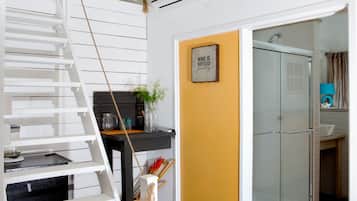 A staircase with a white railing, a black table with a vase and a plant, and a yellow wall with a framed quote.